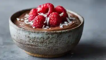 Vegan chocolate mousse in a bowl with coconut whip and raspberries