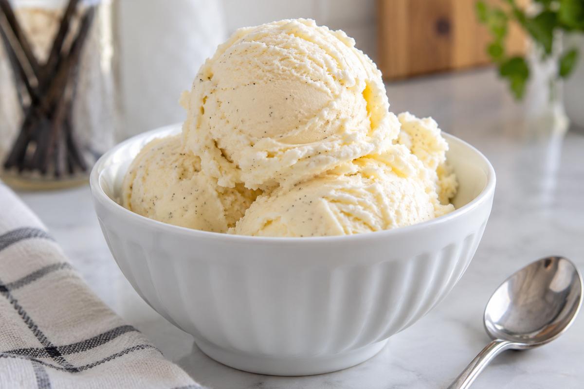 No Churn Ice Cream No Condensed Milk (Easy Vanilla Recipe) 1 Photo of No Churn Ice Cream No Condensed Milk (Easy Vanilla Recipe) (no churn ice cream no condensed milk): A close-up of creamy vanilla no churn ice cream no condensed milk scooped into a chilled white bowl, showing soft rounded scoops, tiny vanilla flecks, and a small silver spoon on a light kitchen counter