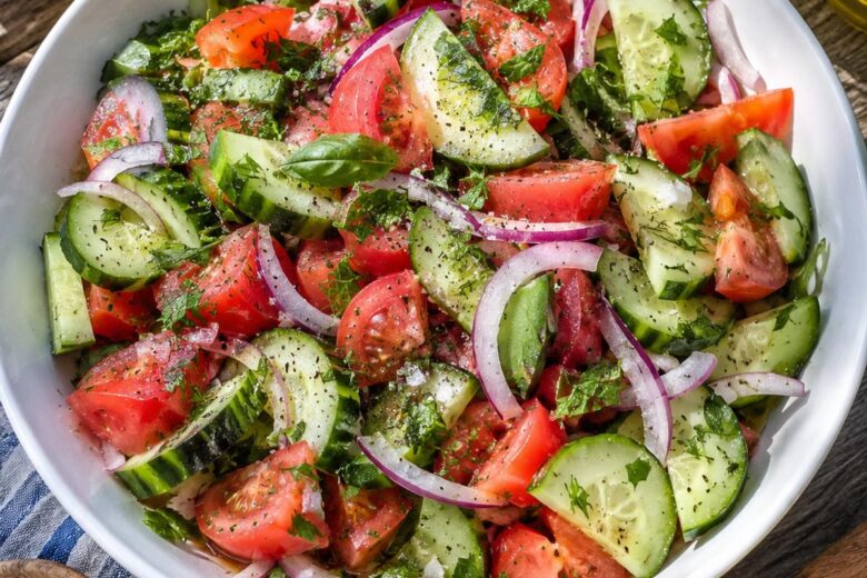 Photo of Summer Cucumber Tomato Salad Recipes: Fresh Lemon Herb Salad (summer cucumber tomato salad recipes): A sunlit overhead view of summer cucumber tomato salad recipes in a wide white serving bowl, with thin cucumber half-moons, chopped ripe red tomatoes, red onion, fresh green herbs, glossy olive oil, and flaky salt on a rustic outdoor table