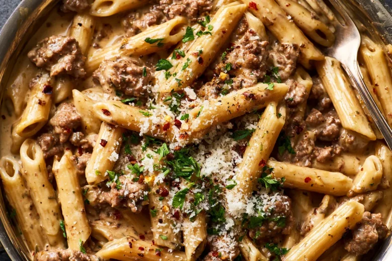 Dinner Recipes Pasta Ground Beef: Creamy Penne 15 Photo of Dinner Recipes Pasta Ground Beef: Creamy Penne (dinner recipes pasta ground beef): A close overhead view of creamy penne pasta with browned ground beef in a garlic cream sauce, topped with grated Parmesan, parsley, and red pepper flakes in a wide skillet, clearly depicting dinner recipes pasta ground beef